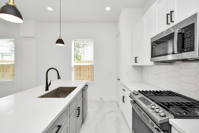 kitchen featuring appliances with stainless steel finishes, hanging light fixtures, sink, white cabinetry, and backsplash