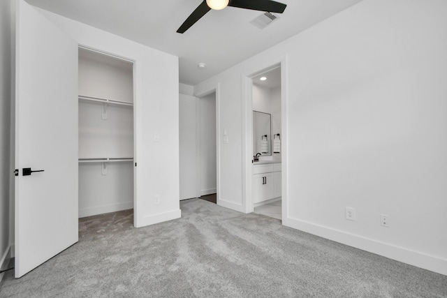 unfurnished bedroom featuring connected bathroom, a closet, ceiling fan, and light colored carpet