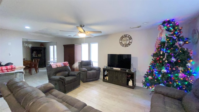 living room with ceiling fan with notable chandelier and light hardwood / wood-style flooring