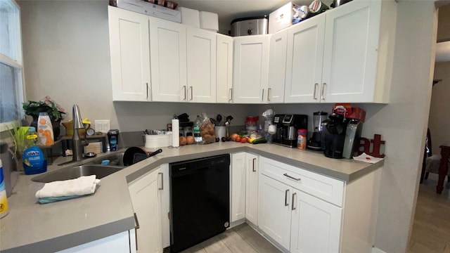 kitchen with white cabinets, black dishwasher, light wood-type flooring, and sink