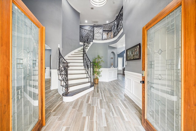 foyer entrance with a towering ceiling and light wood-type flooring