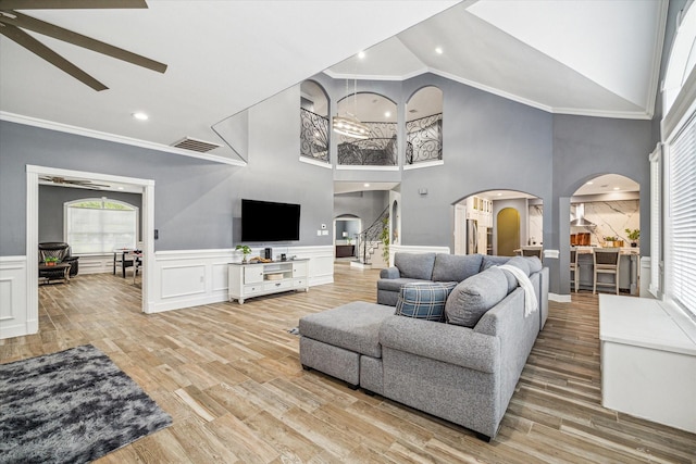 living room with high vaulted ceiling, light wood-type flooring, ceiling fan, and crown molding