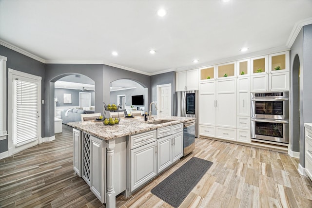 kitchen featuring sink, stainless steel appliances, white cabinetry, light hardwood / wood-style flooring, and an island with sink