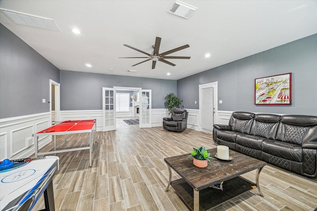 living room with french doors, light wood-type flooring, and ceiling fan