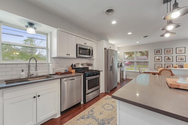 kitchen featuring appliances with stainless steel finishes, pendant lighting, white cabinetry, and sink