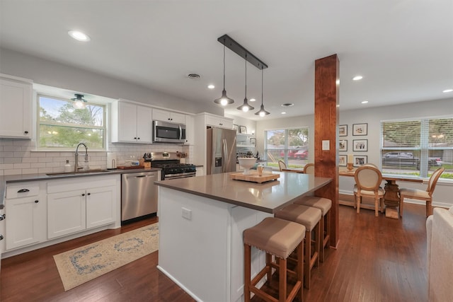 kitchen featuring sink, decorative light fixtures, a kitchen island, a breakfast bar, and appliances with stainless steel finishes