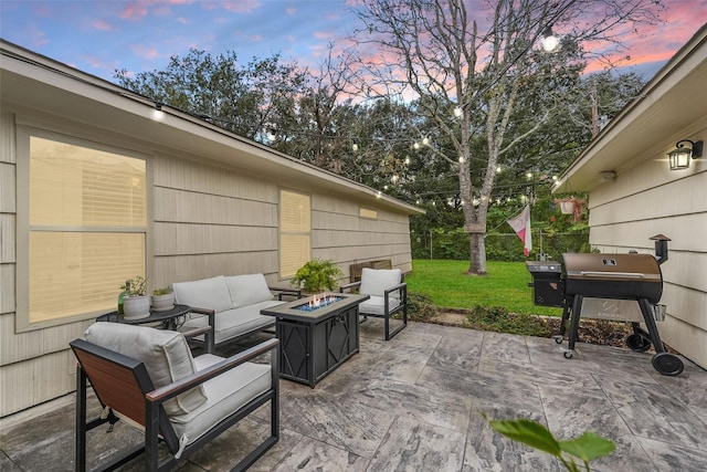 patio terrace at dusk featuring an outdoor living space with a fire pit, a yard, and area for grilling