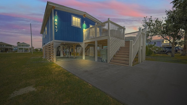 back house at dusk with a carport and a lawn