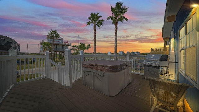 deck at dusk with a hot tub and area for grilling