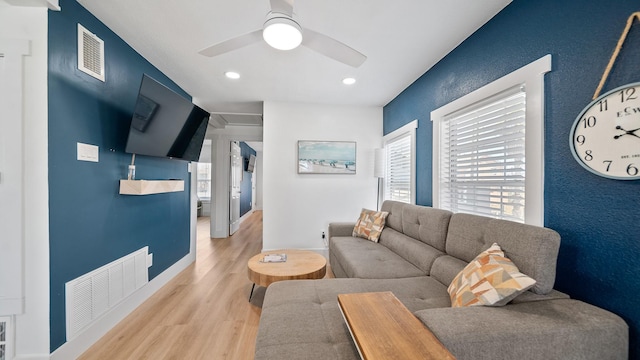 living room with ceiling fan, light wood-type flooring, and a wealth of natural light