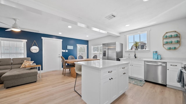 kitchen with stainless steel appliances, white cabinetry, ceiling fan, and light hardwood / wood-style floors