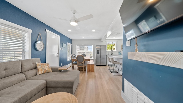 living room featuring light wood-type flooring and ceiling fan