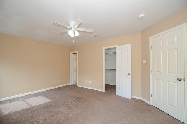 unfurnished bedroom featuring ceiling fan, light colored carpet, and a spacious closet