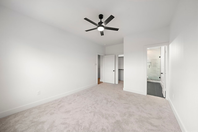 unfurnished bedroom featuring ceiling fan, light colored carpet, ensuite bathroom, and a closet