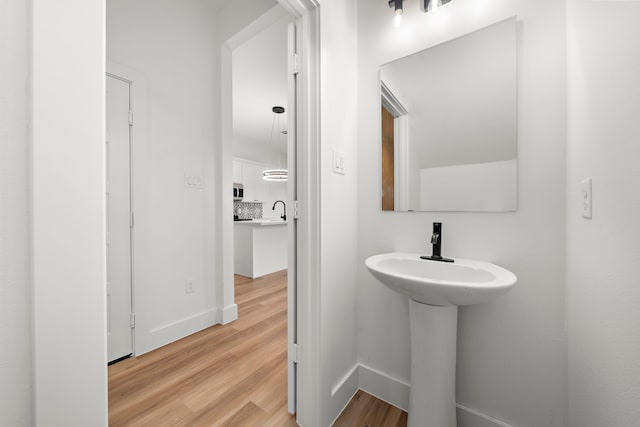 bathroom with sink, decorative backsplash, and hardwood / wood-style floors