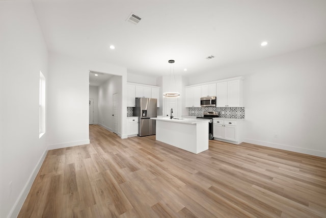 kitchen with stainless steel appliances, sink, white cabinetry, pendant lighting, and a kitchen island with sink