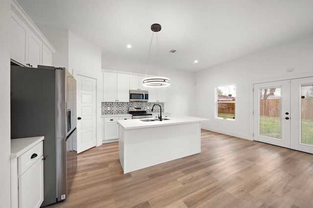 kitchen featuring stainless steel appliances, white cabinetry, a center island with sink, and pendant lighting