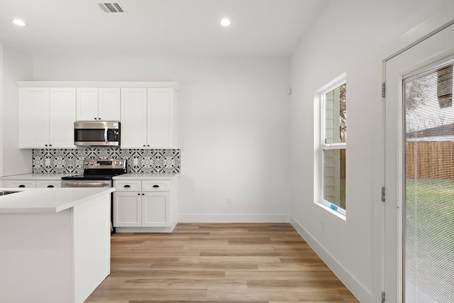 kitchen with white cabinetry, tasteful backsplash, light hardwood / wood-style floors, and appliances with stainless steel finishes