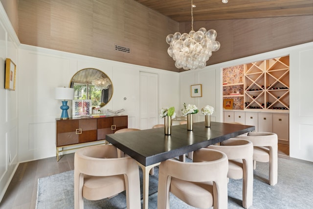 dining area with a towering ceiling, hardwood / wood-style flooring, a notable chandelier, and wood ceiling