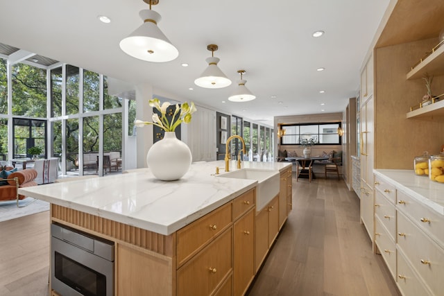 kitchen featuring sink, hanging light fixtures, a kitchen island with sink, and stainless steel microwave