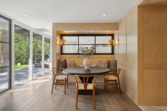 dining area with wood walls, light hardwood / wood-style flooring, expansive windows, and breakfast area