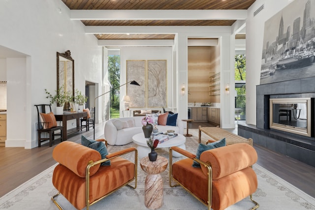 living room featuring wood ceiling, a tile fireplace, beam ceiling, and wood-type flooring