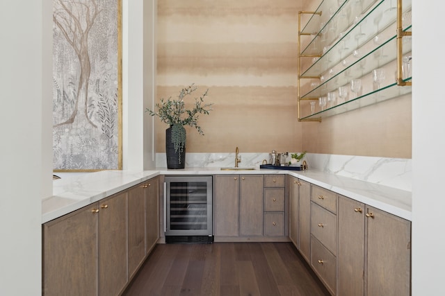 bar featuring sink, light stone countertops, wine cooler, and dark wood-type flooring