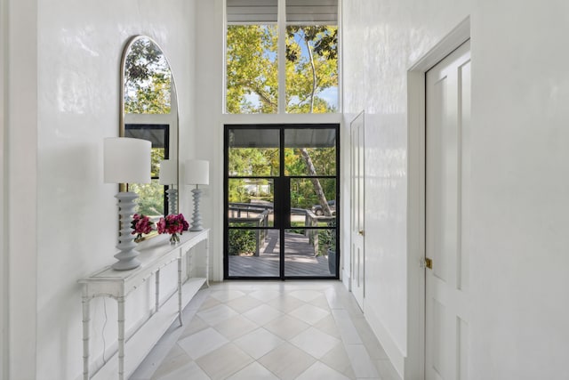 doorway to outside with a towering ceiling and light tile patterned floors