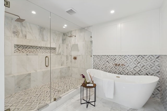 bathroom with tile walls and independent shower and bath