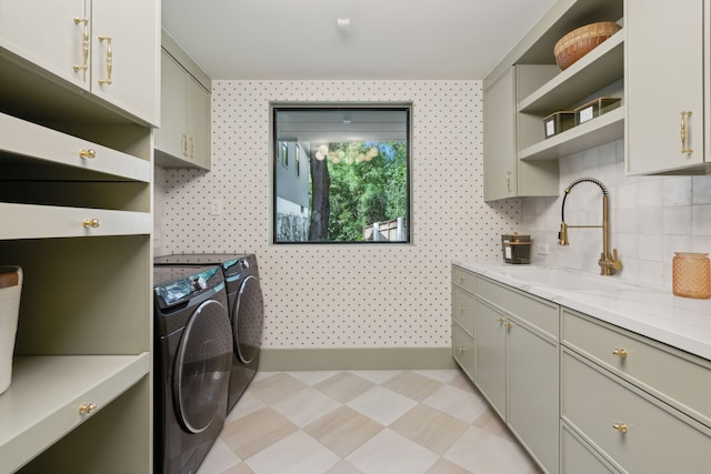 laundry area featuring sink, washer and clothes dryer, and cabinets