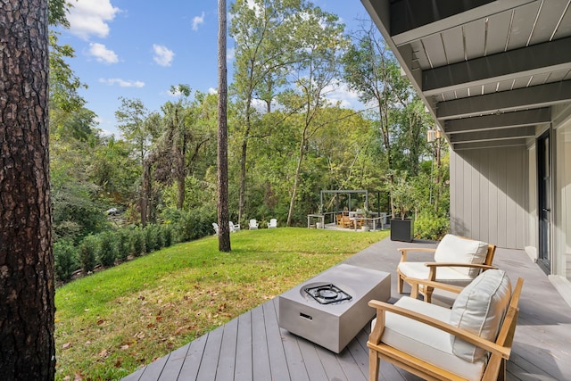 wooden terrace with an outdoor fire pit and a yard