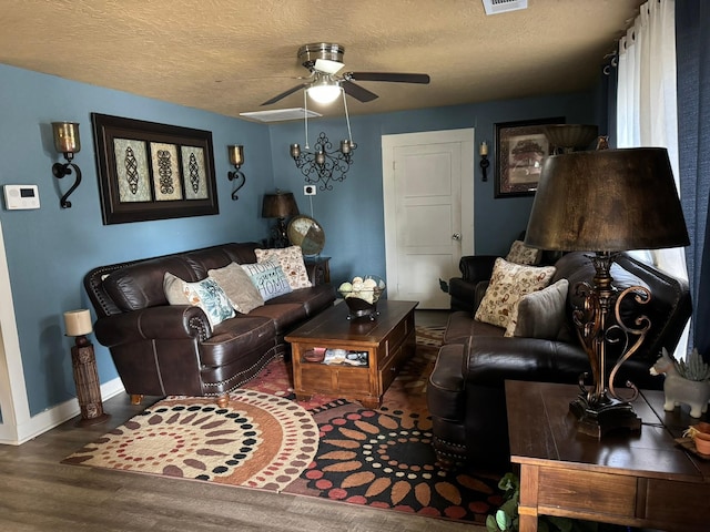 living room featuring dark wood-type flooring, a textured ceiling, and ceiling fan