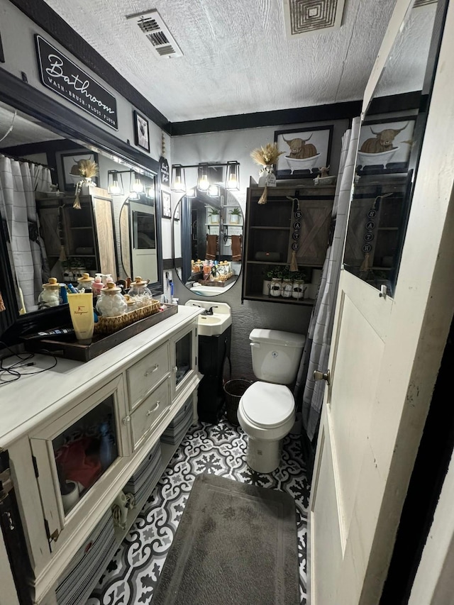 bathroom with toilet, a textured ceiling, and vanity