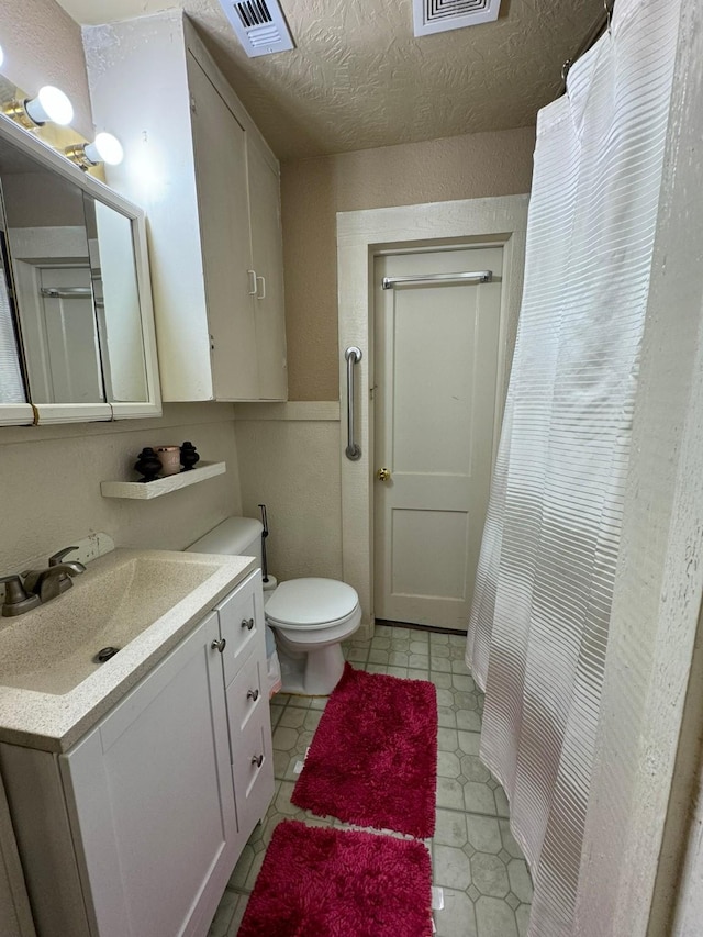 bathroom with toilet, vanity, and a textured ceiling