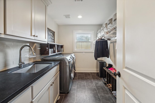 laundry area with washer and dryer, cabinets, dark tile patterned floors, and sink