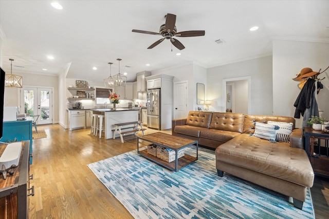 living room featuring ceiling fan, french doors, ornamental molding, and light hardwood / wood-style floors