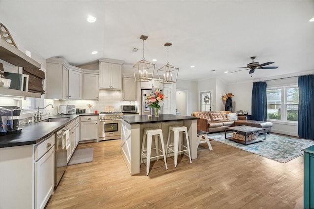 kitchen featuring sink, stainless steel appliances, a center island, and white cabinetry