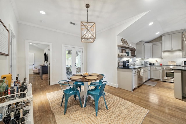 dining room with vaulted ceiling, crown molding, french doors, sink, and light hardwood / wood-style flooring