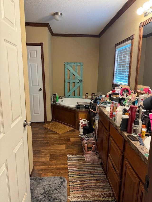 bathroom with ornamental molding, a tub, vanity, and wood-type flooring