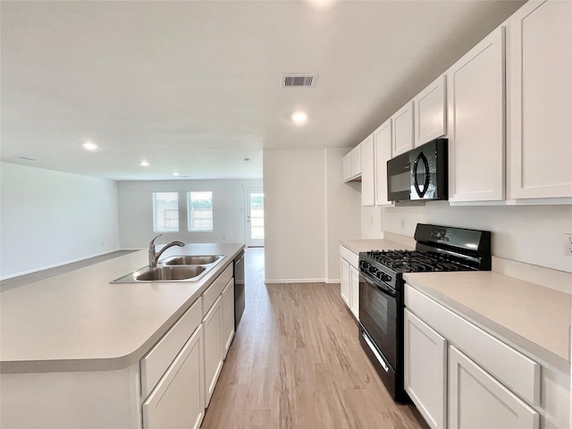 kitchen with sink, white cabinetry, light wood-type flooring, an island with sink, and black appliances