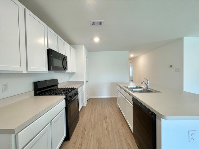 kitchen with sink, white cabinets, light hardwood / wood-style floors, a center island with sink, and black appliances