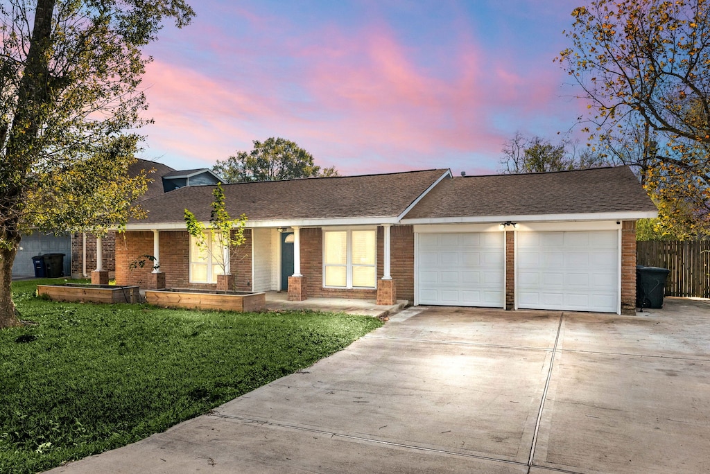 ranch-style home featuring a garage and a yard