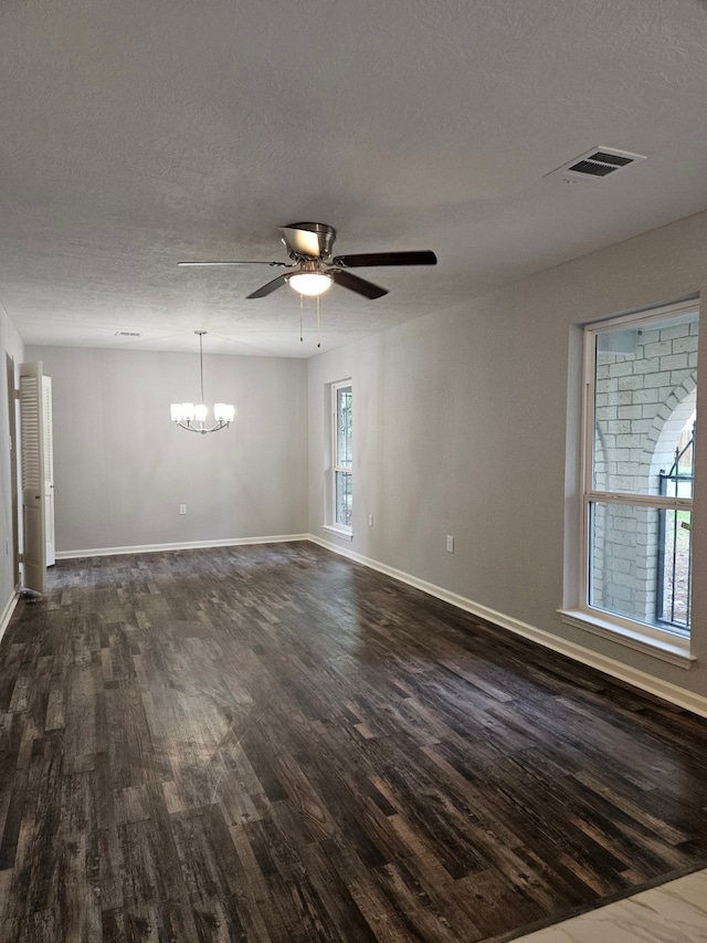 spare room featuring a textured ceiling, dark wood-type flooring, and ceiling fan with notable chandelier