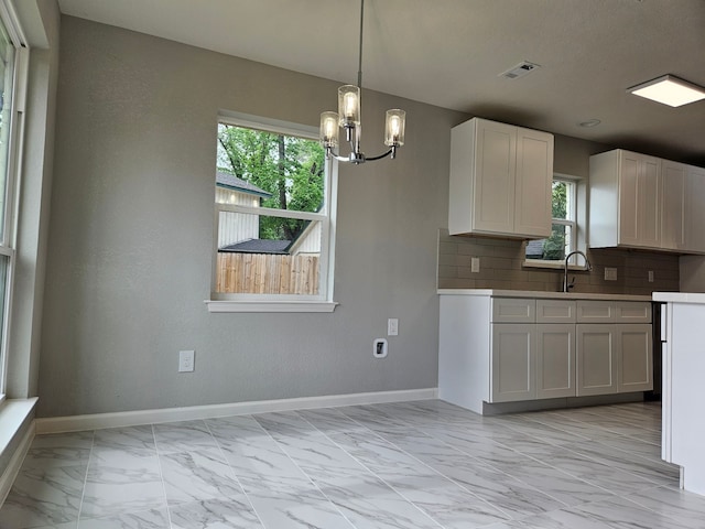 kitchen with hanging light fixtures, white cabinetry, a chandelier, and tasteful backsplash