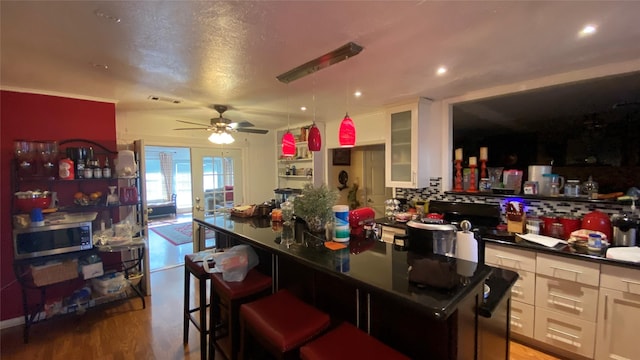 kitchen with a kitchen island, decorative backsplash, white cabinetry, and hardwood / wood-style flooring