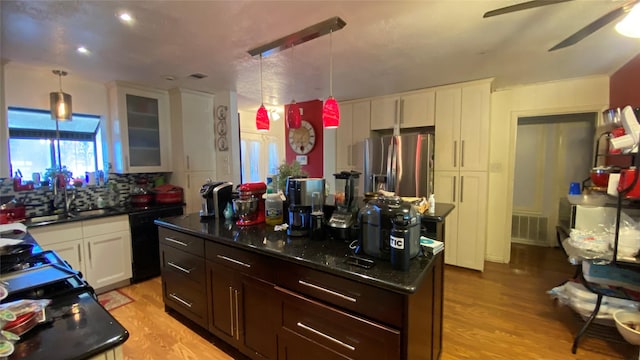 kitchen with white cabinets, black dishwasher, decorative backsplash, hanging light fixtures, and stainless steel fridge