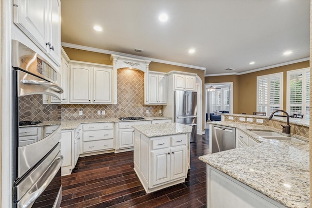 kitchen featuring white cabinets, stainless steel appliances, light stone counters, sink, and tasteful backsplash