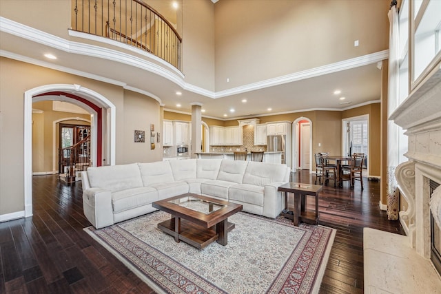 living room featuring a high ceiling, crown molding, dark hardwood / wood-style floors, and a fireplace