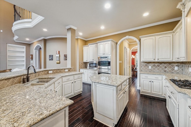 kitchen featuring appliances with stainless steel finishes, crown molding, light stone countertops, sink, and tasteful backsplash