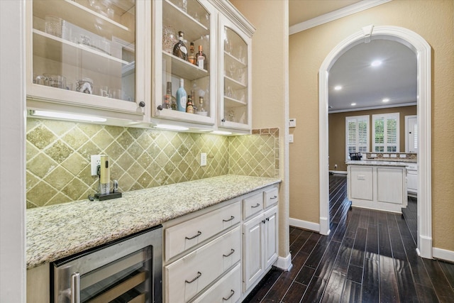 bar featuring light stone countertops, wine cooler, white cabinets, and ornamental molding